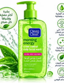 Green bottle of Clean & Clear Morning Energy daily facial wash with pump, surrounded by water splashes and green leaves.