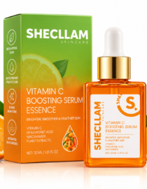 SHEGLAM Skincare Vitamin C boosting serum essence in an orange bottle beside a green–orange box with orange slices nearby