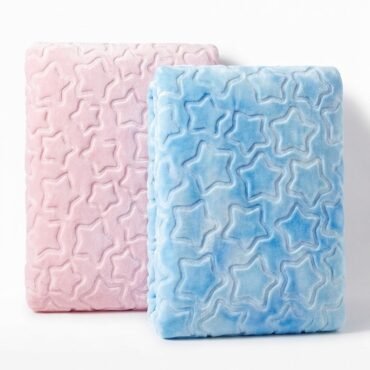 Two plush star-patterned blankets, pink and blue, folded and standing on a white surface.