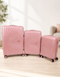 Three pink hard shell suitcases of different sizes aligned on a white background wheels visible with a radial pattern on the shells