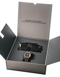 Gold tone wristwatch and sunglasses displayed in an open black presentation box