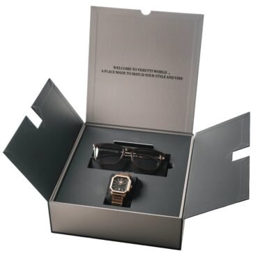 Gold-tone wristwatch and sunglasses displayed in an open black presentation box.