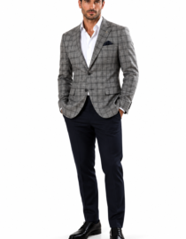 Man in a tailored gray plaid blazer white shirt navy trousers and black dress shoes standing with hands in pockets against a white background
