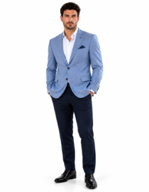 Man modeling a light blue blazer with white shirt navy trousers and black dress shoes standing with hands in pockets against a white background