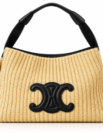 Straw colored woven handbag with a black leather handle and a large black decorative logo on the front