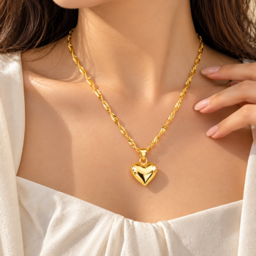 Gold heart pendant on a twisted rope gold chain resting on a woman's décolletage.