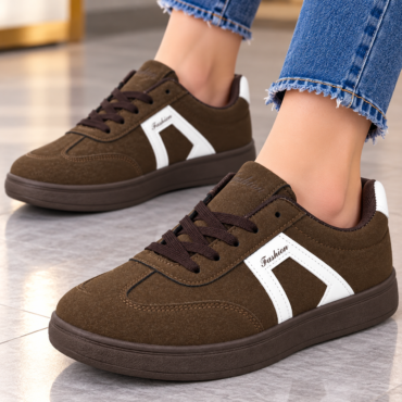 Brown suede sneakers with white side panels and brown laces on a tiled floor, worn with frayed-hem jeans.