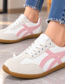 White sneakers with pink side stripes and white laces on a gum sole worn with frayed hem jeans