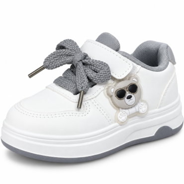 White children's sneaker with a chunky sole, gray braided laces, and a plastic bear charm wearing sunglasses on the side.