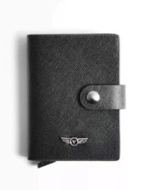 verutti-mens-leather-wallet-black-vrw-1012-7jpg - المول الشامل في الاردن Close up of a black textured wallet with a snap strap and a small winged metal logo near the bottom