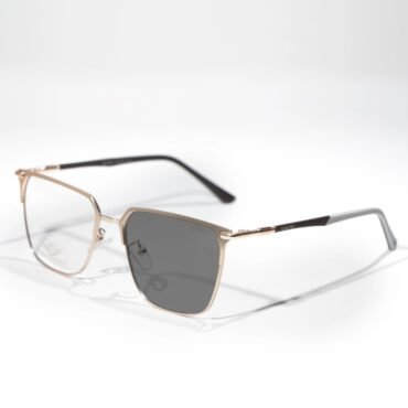 Gold-framed rectangular eyeglasses with dark lenses resting on a white surface.