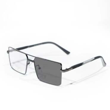 Metal-framed sunglasses with rectangular dark lenses resting on a white surface, close-up view