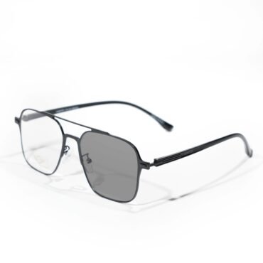 Black rectangular eyeglasses with thin metal frame resting on a white surface, lens glare visible, brand name on temple partially shown (Verutti).