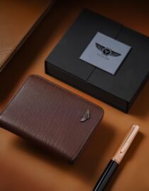 Brown textured leather wallet with even stitching placed on a tan surface beside a black box and a goldtipped pen 7
